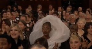 Cantora vira meme por atrapalhar visão na premiação do Oscar, entenda!A cantora Tems ficou marcada na história por usar um vestido que ocupava bastante espaço